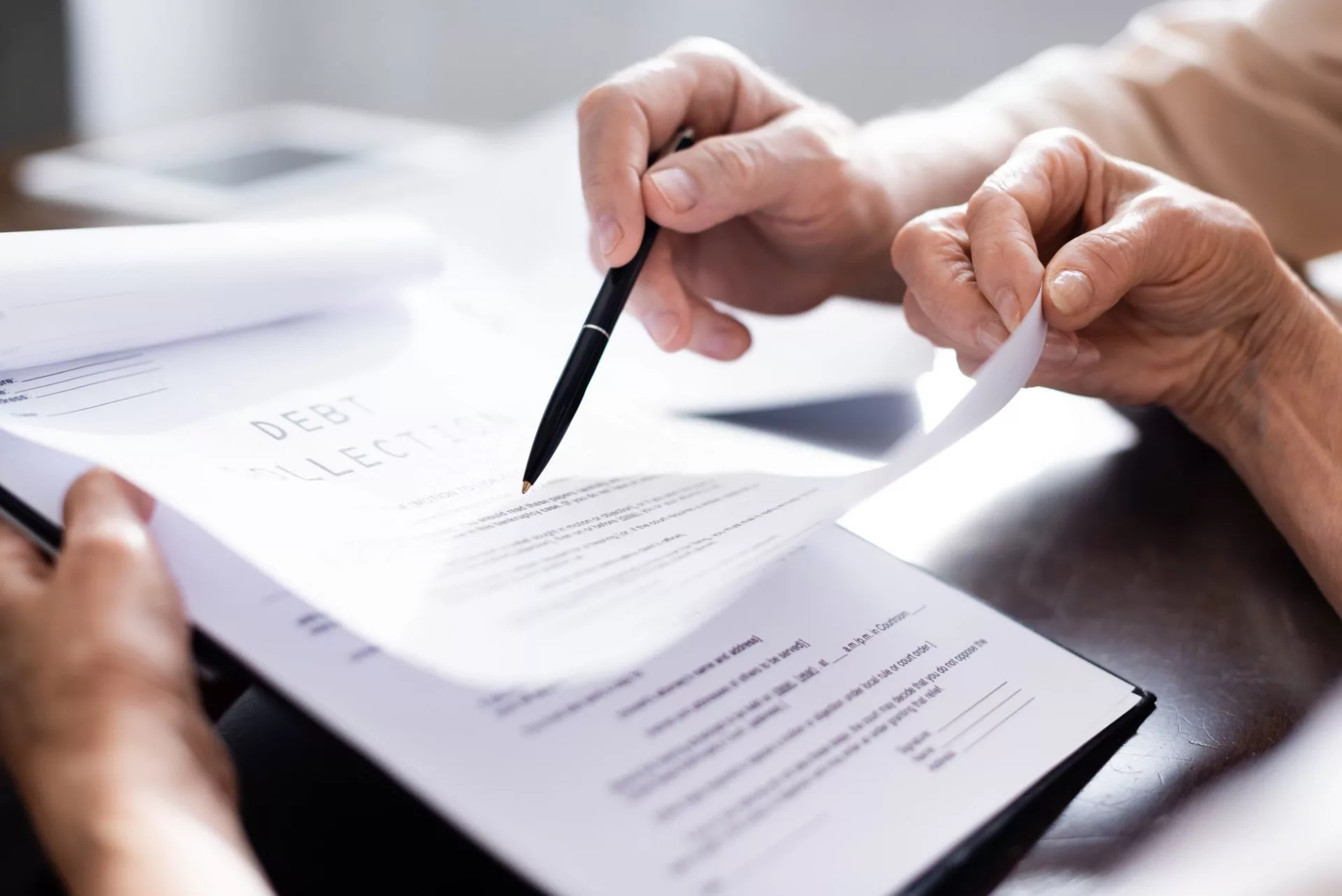Cropped view of elderly couple holding pen and documents with debt collection lettering at home